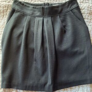 Short black fully lined skirt with front pleated and back darts.